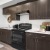 Studios in San Jose CA - Virginia Street Studios - A Spacious Kitchen With Dark Cabinetry, Wood-Style Flooring- Black Appliances, And White Countertops